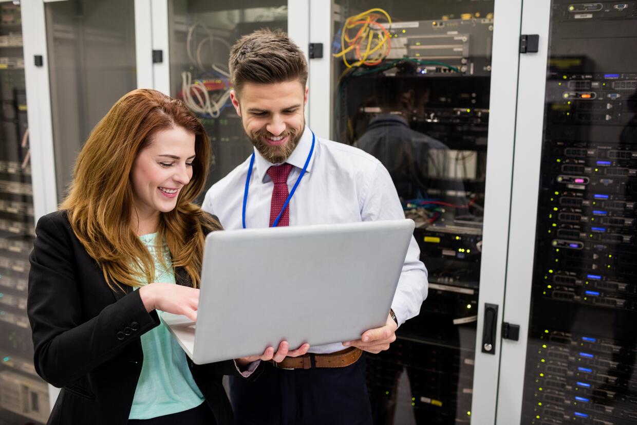 TECHNICIANS USING LAPTOP WHILE ANALYZING SERVER IN SERVER ROOM